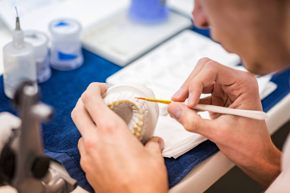 a Prosthodontist in Pompano Beach works on a set of removable dentures